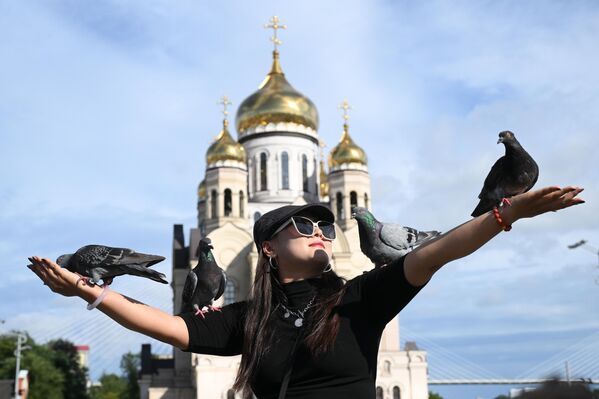 Du khách đang cho chim bồ câu ăn tại Quảng trường Chiến sĩ Cách mạng ở Vladivostok - Sputnik Việt Nam