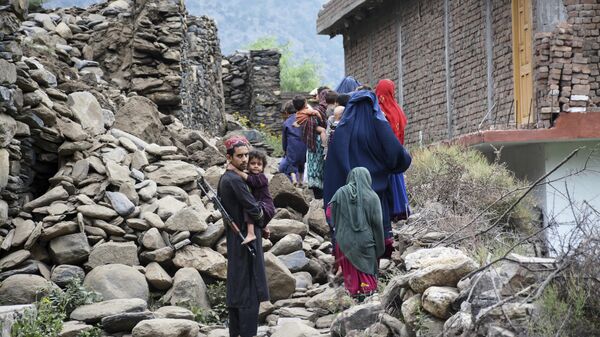 Người dân địa phương đi ngang qua một ngôi nhà bị phá hủy bởi trận động đất ở Mazar Dara, tỉnh Kunar, Afghanistan. - Sputnik Việt Nam