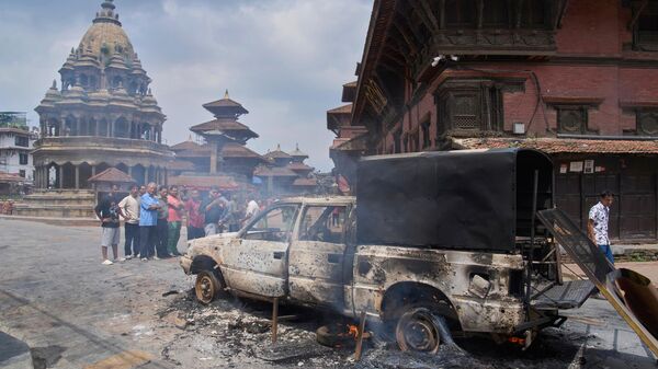 Người dân nhìn chiếc xe cảnh sát bị cháy trong cuộc biểu tình phản đối lệnh cấm mạng xã hội và tham nhũng ở Kathmandu, Nepal, thứ Ba, ngày 9 tháng 9 năm 2025. - Sputnik Việt Nam