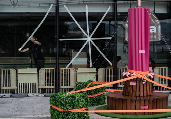 Nhân viên nhà hàng ở Hồng Kông dán băng dính lên kính để bảo vệ khỏi gió mạnh trước khi siêu bão “Ragasa” tiến gần - Sputnik Việt Nam