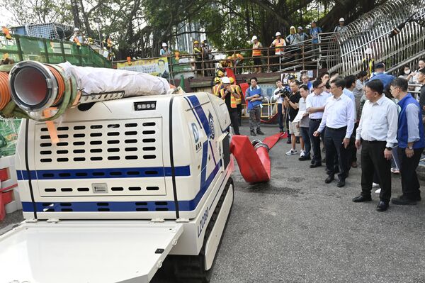 Chánh Văn phòng Hành chính Hồng Kông Eric Chan Kwok-ki (người thứ hai từ phải sang) kiểm tra thiết bị chống gió và chống nước trước khi siêu bão “Ragasa” tiến gần - Sputnik Việt Nam