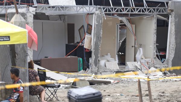 Người dân ngồi cạnh một ngôi nhà bị hư hại sau trận động đất mạnh ở thành phố Davao, miền nam Philippines - Sputnik Việt Nam