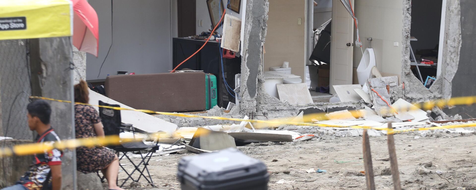 Người dân ngồi cạnh một ngôi nhà bị hư hại sau trận động đất mạnh ở thành phố Davao, miền nam Philippines - Sputnik Việt Nam, 1920, 10.10.2025