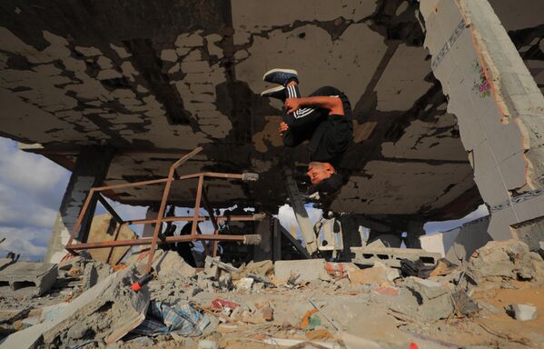 Các vận động viên trẻ người Palestine trình diễn kỹ thuật parkour giữa đống đổ nát của những tòa nhà bị phá hủy ở khu vực Al-Mugraqa sau lệnh ngừng bắn ở Thành phố Gaza. - Sputnik Việt Nam