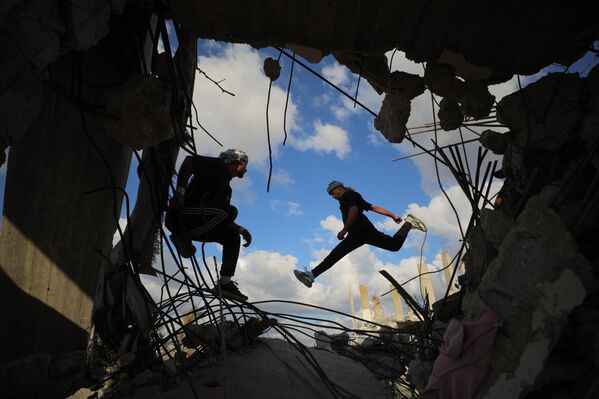 Các vận động viên trẻ người Palestine trình diễn kỹ thuật parkour giữa đống đổ nát của những tòa nhà bị phá hủy ở khu vực Al-Mugraqa sau lệnh ngừng bắn ở Thành phố Gaza. - Sputnik Việt Nam