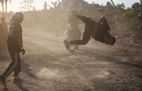 Các vận động viên trẻ người Palestine trình diễn kỹ thuật parkour giữa đống đổ nát của những tòa nhà bị phá hủy ở khu vực Al-Mugraqa sau lệnh ngừng bắn ở Thành phố Gaza. - Sputnik Việt Nam