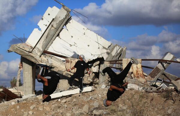 Các vận động viên trẻ người Palestine trình diễn kỹ thuật parkour giữa đống đổ nát của những tòa nhà bị phá hủy ở khu vực Al-Mugraqa sau lệnh ngừng bắn ở Thành phố Gaza. - Sputnik Việt Nam