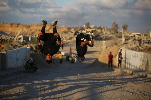 Các vận động viên trẻ người Palestine trình diễn kỹ thuật parkour giữa đống đổ nát của những tòa nhà bị phá hủy ở khu vực Al-Mugraqa sau lệnh ngừng bắn ở Thành phố Gaza. - Sputnik Việt Nam