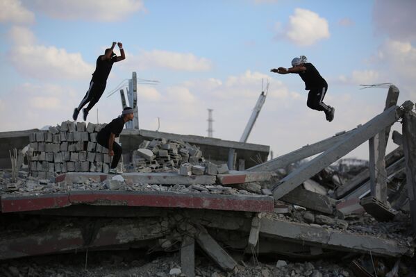 Các vận động viên trẻ người Palestine trình diễn kỹ thuật parkour giữa đống đổ nát của những tòa nhà bị phá hủy ở khu vực Al-Mugraqa sau lệnh ngừng bắn ở Thành phố Gaza. - Sputnik Việt Nam