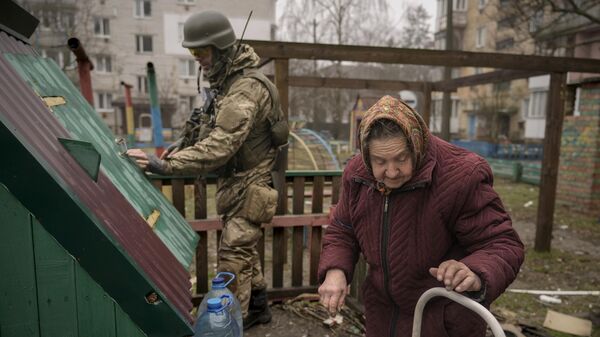 Một người lính Ukraine đang giúp một phụ nữ lớn tuổi lấy nước từ giếng gần Kiev - Sputnik Việt Nam
