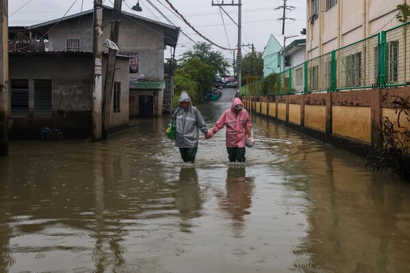Một cặp vợ chồng đi bộ trên con đường ngập nước tại Bulacan, khi siêu bão Fung-wong ập vào Philippines - Sputnik Việt Nam