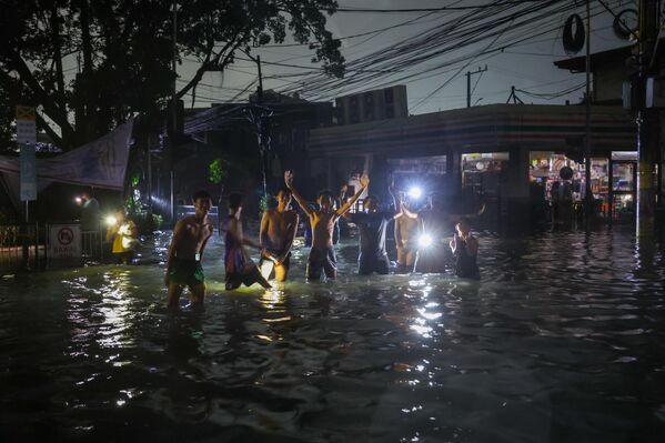 - Những người trẻ tuổi đi trên con đường ngập nước trong siêu bão Fung-wong tại Manila, Philippines - Sputnik Việt Nam