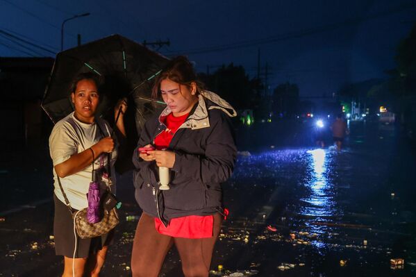 Những người phụ nữ chờ nước rút tại khu vực ngập lụt mất điện trong siêu bão Fung-wong tại Manila, Philippines - Sputnik Việt Nam