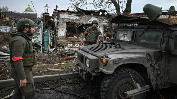 Quân nhân Lực lượng vũ trang Nga gần một chiếc xe bọc thép Humvee bị hư hỏng ở thành phố Sudzha - Sputnik Việt Nam