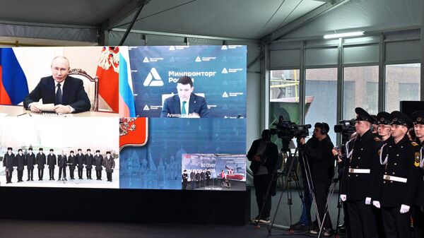 Tổng thống Nga Vladimir Putin phát biểu qua video trong buổi lễ đặt ky tàu phá băng hạt nhân Stalingrad tại St. Petersburg. Bên phải: Bộ trưởng Công nghiệp và Thương mại Nga Anton Alikhanov. - Sputnik Việt Nam