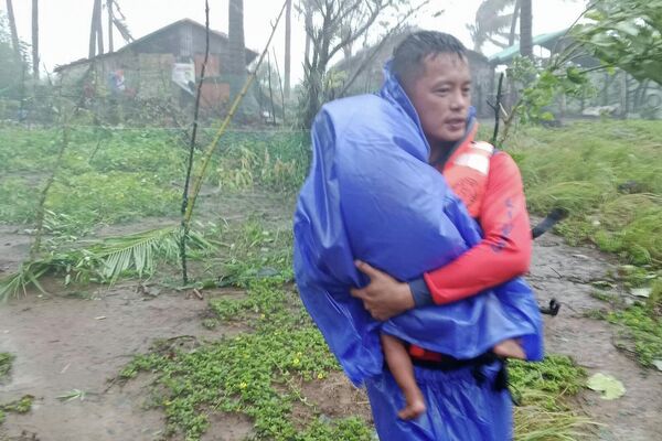 Lực lượng cứu hộ di tản em nhỏ đến nơi an toàn khi siêu bão Ragasa đổ bộ vào Santa Ana, tỉnh Cagayan, miền bắc Philippines, ngày 22 tháng 9 năm 2025 - Sputnik Việt Nam