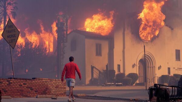 Người đàn ông đi ngang qua nhà thờ Altadena Community đang bốc cháy dữ dội do các đám cháy rừng ở trung tâm thành phố Altadena, Pasadena, California, Mỹ - Sputnik Việt Nam