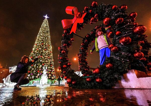 Người dân chụp ảnh bên cây thông Noel tại Quảng trường Tháng Mười ở Minsk - Sputnik Việt Nam