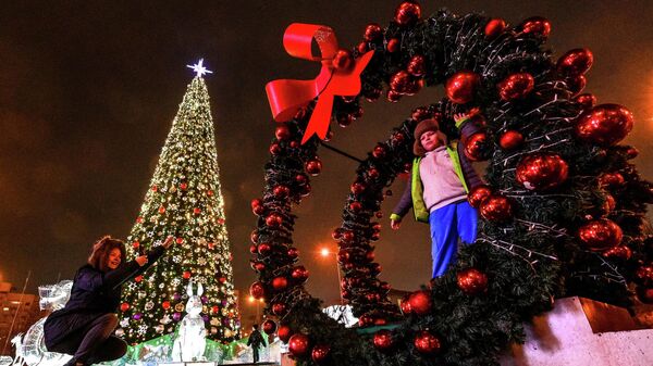 Người dân chụp ảnh bên cây thông Noel tại Quảng trường Tháng Mười ở Minsk - Sputnik Việt Nam