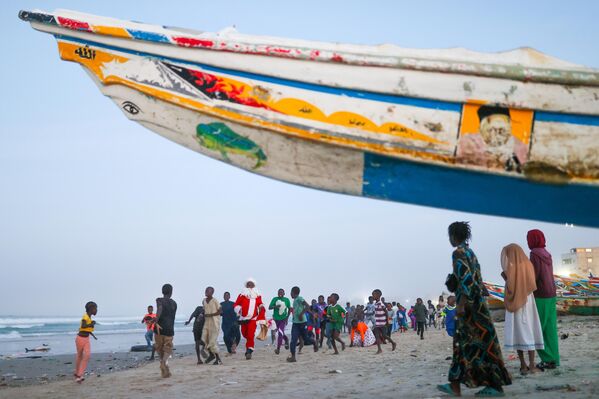 Nghệ sĩ biểu diễn đường phố Thierno Guiré hóa thân thành ông già Noel, đi qua những khu phố nghèo ở Dakar (Senegal), phát kẹo cho trẻ em trước Giáng sinh - Sputnik Việt Nam