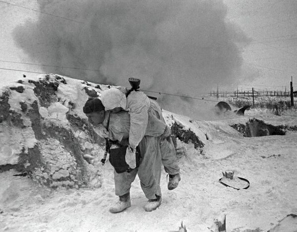 Một nhân viên y tế Liên Xô cõng chiến sĩ bị thương rời khỏi chiến trường trong trận chiến ở ngoại vi Leningrad - Sputnik Việt Nam