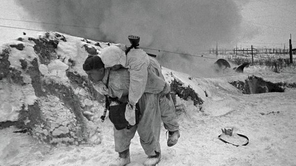 Một nhân viên y tế Liên Xô cõng chiến sĩ bị thương rời khỏi chiến trường trong trận chiến ở ngoại vi Leningrad - Sputnik Việt Nam