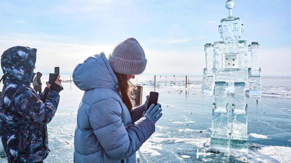 Những người tham gia Lễ hội nghệ thuật băng giá mùa đông lần thứ XII Sống trên Baikal 2026 bên tác phẩm điêu khắc hình robot - Sputnik Việt Nam