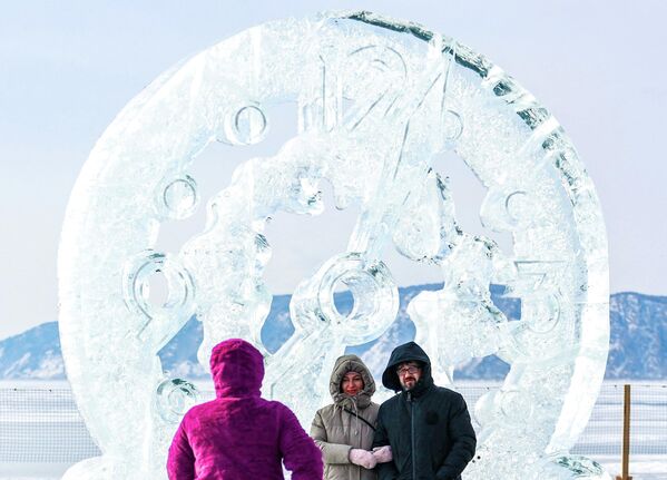 Những người tham gia Lễ hội nghệ thuật băng giá mùa đông lần thứ XII "Sống trên Baikal" 2026 bên tác phẩm điêu khắc "Giờ vàng" - Sputnik Việt Nam