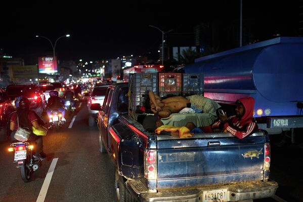 Người đàn ông ngủ trong thùng xe bán tải bị mắc kẹt trong đám đông tại Caracas, Venezuela - Sputnik Việt Nam