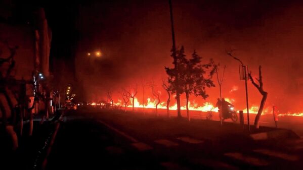 Một chiếc xe máy đi ngang qua Đại lộ Koohsar đang bốc cháy ở Tehran, Iran - Sputnik Việt Nam
