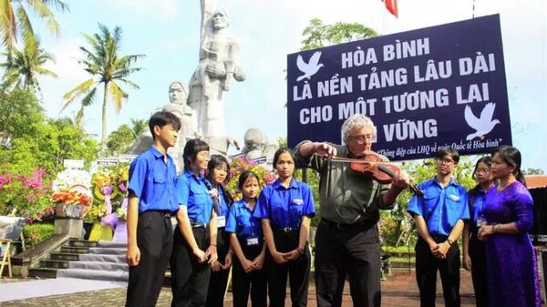 Ông Mike Boehm đến từ tổ chức Madison Quakers kéo tiếng vĩ cầm dưới chân tượng đài Sơn Mỹ với chủ đề “Tiếng vĩ cầm ở Mỹ Lai” để tưởng nhớ các nạn nhân - Sputnik Việt Nam