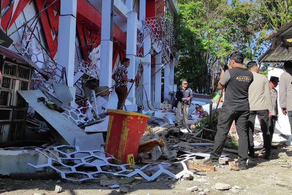 Một nhân viên cảnh sát đang kiểm tra xem xét tòa nhà bị hư hại do động đất ở tỉnh Bắc Sulawesi, Indonesia. - Sputnik Việt Nam