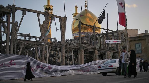 Người qua đường đi ngang khu phức hợp Grand Hosseiniya bị phá hủy do các cuộc không kích của Mỹ và Israel ở Zanjan, Iran. - Sputnik Việt Nam