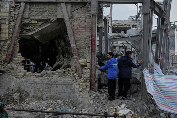 Hai người đàn ông kiểm tra một tòa nhà bị phá hủy trong khu phức hợp Grand Hosseiniya bị hư hại do các cuộc không kích của Mỹ và Israel ở Zanjan, Iran. - Sputnik Việt Nam