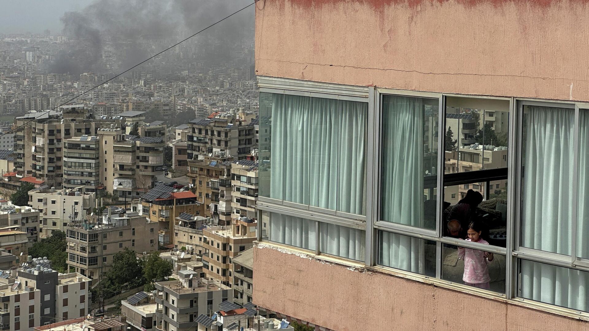 Một cô gái nhìn ra ngoài cửa sổ khi khói bốc lên sau cuộc không kích của Israel vào vùng ngoại ô phía nam Beirut, Lebanon Một cô gái nhìn ra ngoài cửa sổ khi khói bốc lên sau cuộc không kích của Israel vào vùng ngoại ô phía nam Beirut, Lebanon - Sputnik Việt Nam, 1920, 10.04.2026