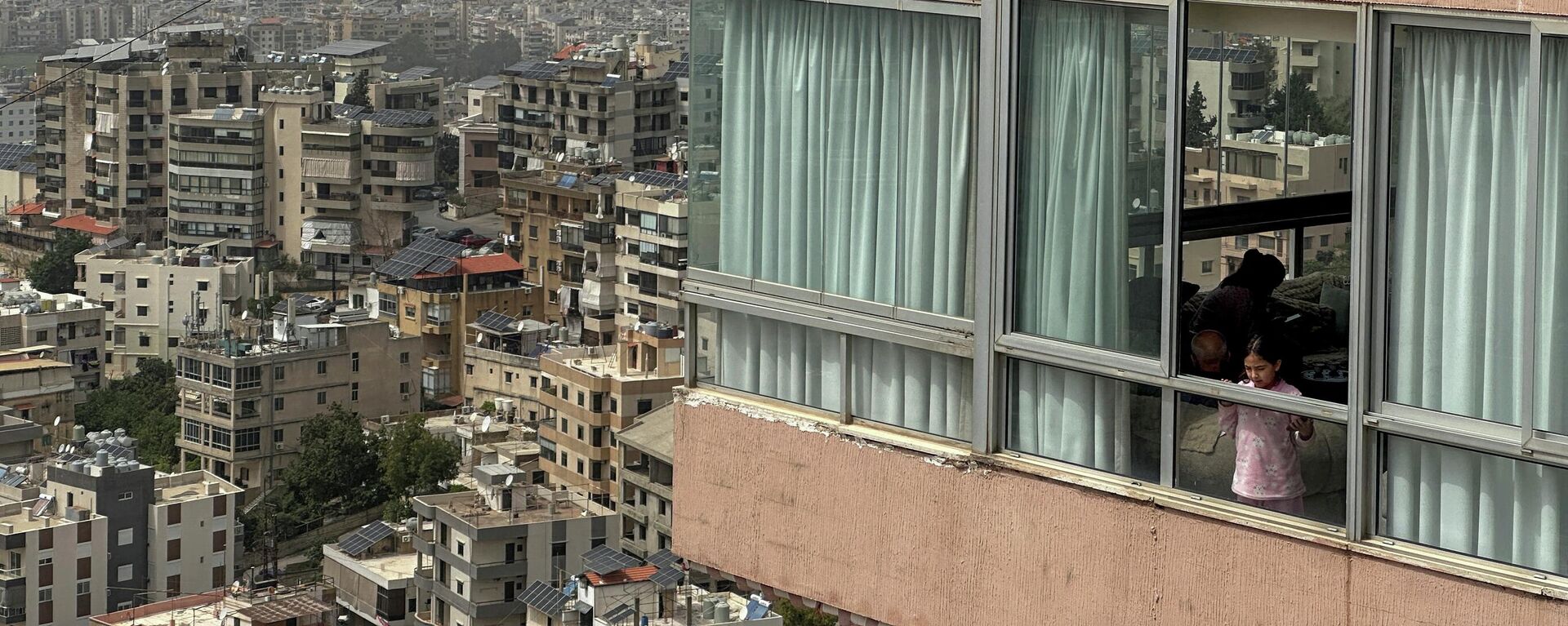 Một cô gái nhìn ra ngoài cửa sổ khi khói bốc lên sau cuộc không kích của Israel vào vùng ngoại ô phía nam Beirut, Lebanon - Sputnik Việt Nam, 1920, 10.04.2026