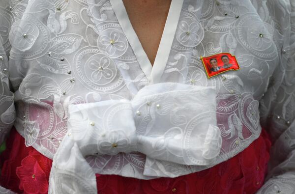 Người dân Bình Nhưỡng đeo huy hiệu có chân dung các nhà lãnh đạo Kim Jong Il và Kim Il Sung (Kim Nhật Thành). - Sputnik Việt Nam