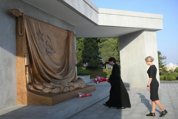 Linh mục Andrei Kalchev, trưởng đoàn đại biểu Giáo phận Vladivostok (Liên bang Nga), cùng vợ trong buổi lễ đặt hoa tại Đài tưởng niệm Giải phóng ở Bình Nhưỡng. - Sputnik Việt Nam