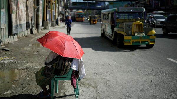 Một người bán hàng rong dùng ô che nắng trên đường phố ở Manila, Philippines. - Sputnik Việt Nam