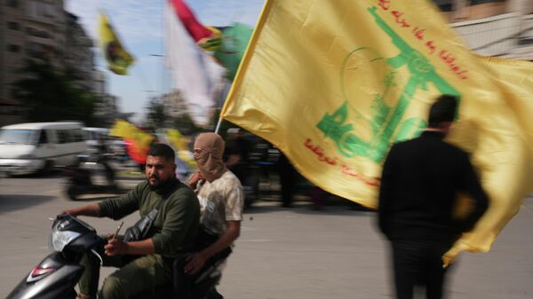 Đàn ông lái xe máy lấy lá cờ Hezbollah trong khi cuộc họp nhỏ tại Dahiyeh, ngoại ô nam Beirut, Lebanon, ngày thứ bảy, 25, tháng tư, năm 2026 - Sputnik Việt Nam