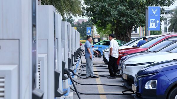 Người dân sử dụng trạm sạc để nạp điện cho phương tiện tại khu đô thị phía Tây Hà Nội, cho thấy nhu cầu sử dụng năng lượng xanh ngày càng tăng - Sputnik Việt Nam