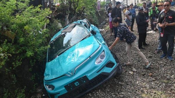 Người dân quan sát thiệt hại đối với một chiếc taxi điện Green SM sau vụ va chạm với tuyến đường sắt ngoại ô KRL và tàu Argo tại Bromo Anggrek, Indonesia. - Sputnik Việt Nam