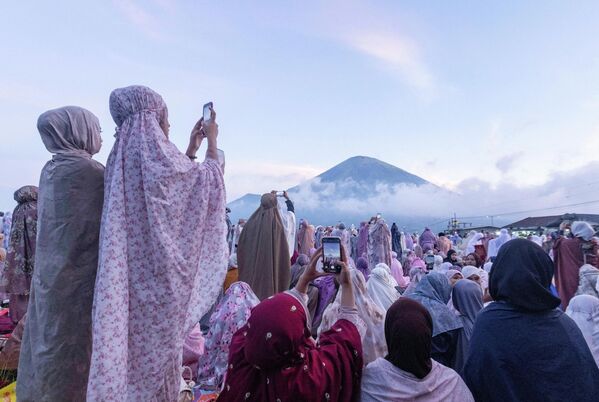 Phụ nữ Hồi giáo Indonesia chụp ảnh lưu niệm với núi Sindoro phía sau trước giờ hành lễ cầu nguyện tập thể nhân dịp Eid al-Adha, Indonesia. - Sputnik Việt Nam