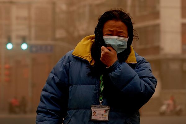 Người phụ nữ đeo khẩu trang bảo vệ trong cơn bão cát ở Bắc Kinh, năm 2021. - Sputnik Việt Nam