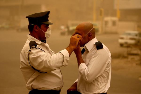 Sĩ quan cảnh sát Iraq giúp đồng nghiệp đeo khẩu trang trong cơn bão cát ở Baghdad, Iraq, năm 2008. - Sputnik Việt Nam