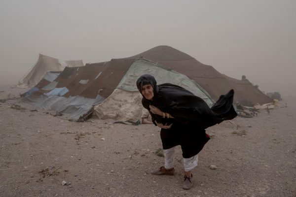Người phụ nữ Afghanistan đi bộ gần lều của mình trong trận bão cát ở làng Chahak sau trận động đất ở quận Zenda Jan thuộc tỉnh Herat, Afghanistan, năm 2023. - Sputnik Việt Nam