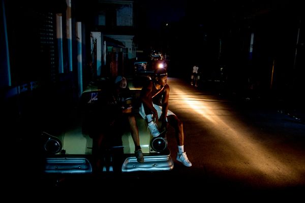 Những người đàn ông ngồi trên cốp xe ô tô trong lúc mất điện ở Havana. - Sputnik Việt Nam