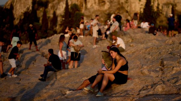 Du khách dùng quạt giải nhiệt trong đợt nắng nóng tại đồi Areopagus, với Acropolis ở phía sau, ở Athens (Hy Lạp). - Sputnik Việt Nam