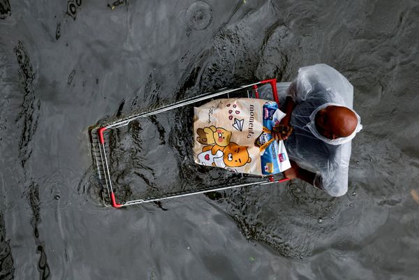 Người đàn ông xách đồ mua sắm trên con phố ngập nước ở Bangkok. - Sputnik Việt Nam