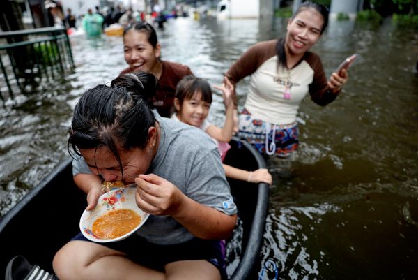 Người phụ nữ ăn mì trong chiếc chậu trên đường phố ngập nước ở Bangkok. - Sputnik Việt Nam